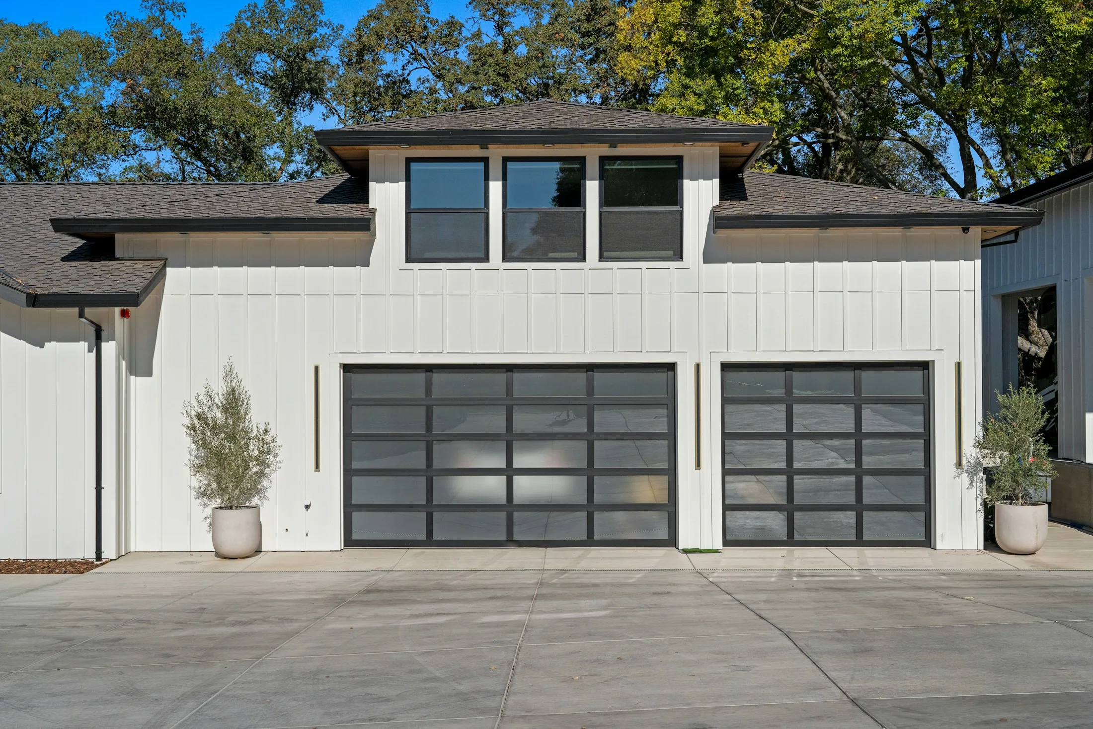 Two complete glass garage doors with dark horizontal frames set into a contemporary white facade.
